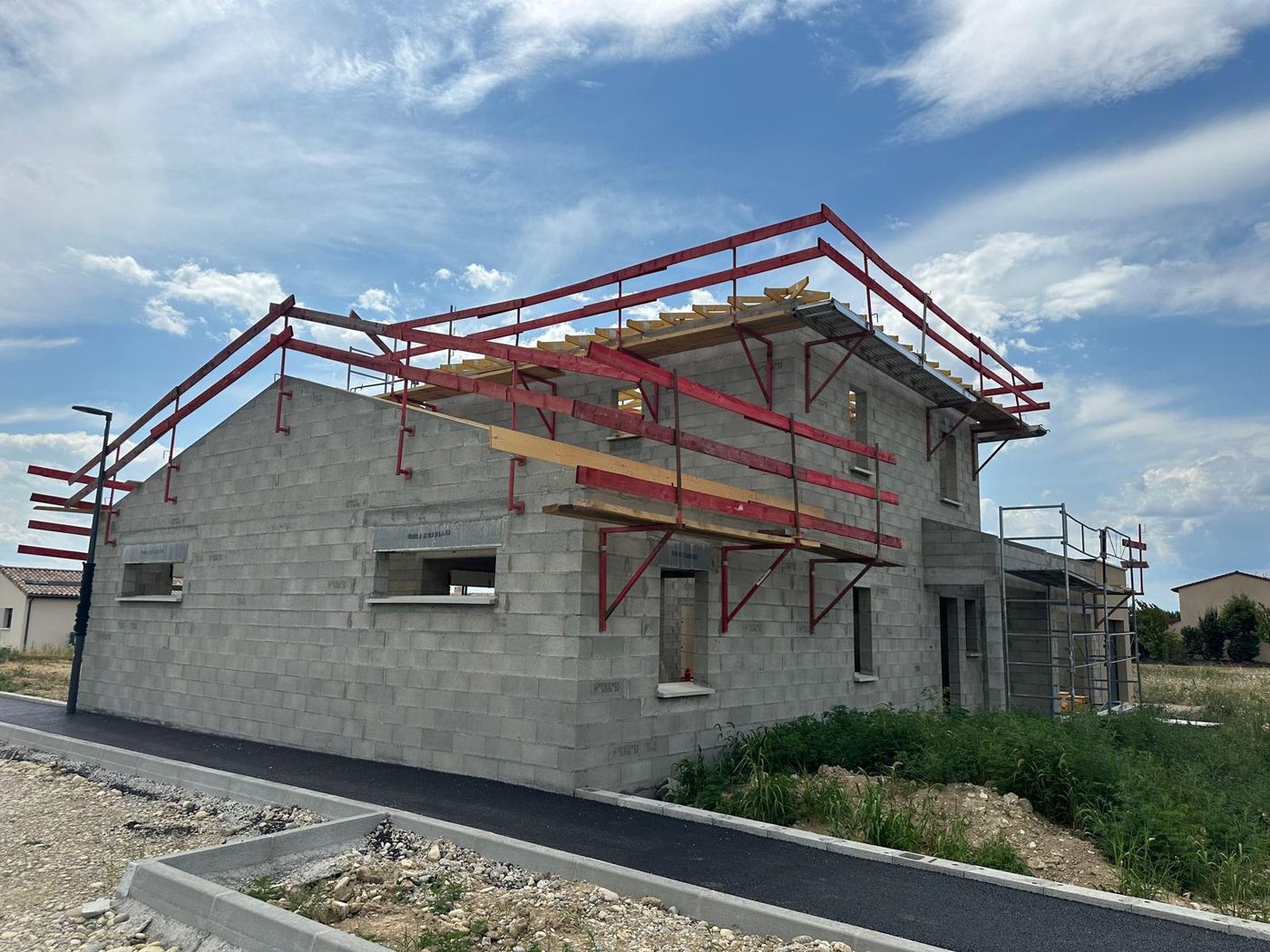 Élévation des murs en parpaing d'une maison avec échafaudage de sécurité et pose de la charpente